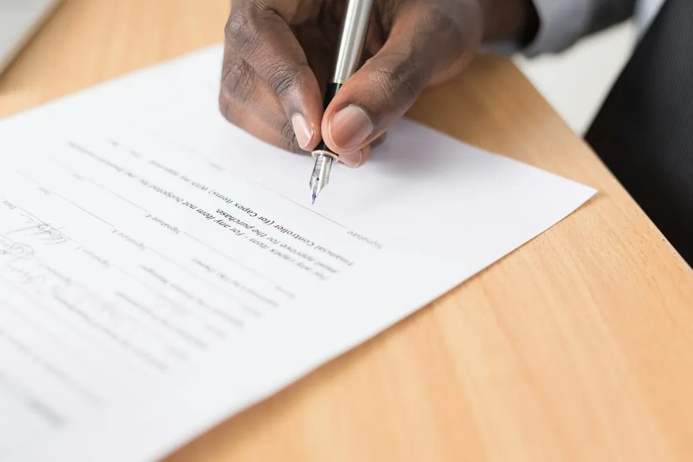 Hand unterschreibt ein Dokument mit Füller