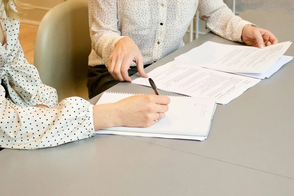 Frau unterschreibt am Tisch ein Dokument
